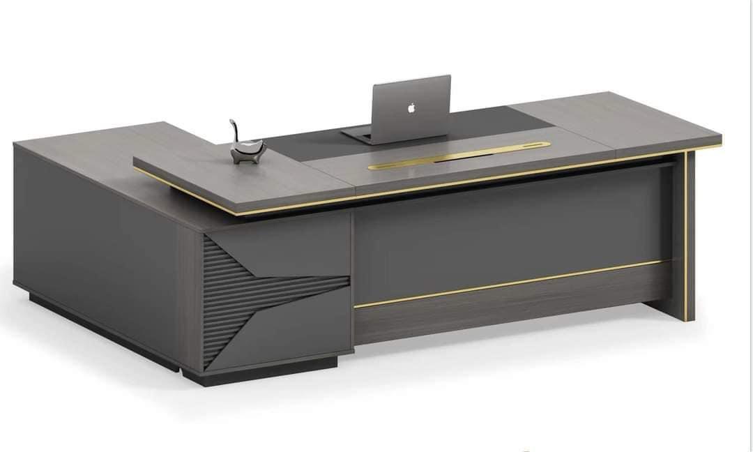 "A modern grey and charcoal executive desk featuring subtle gold trim, a black writing mat, and a matching side return cabinet."