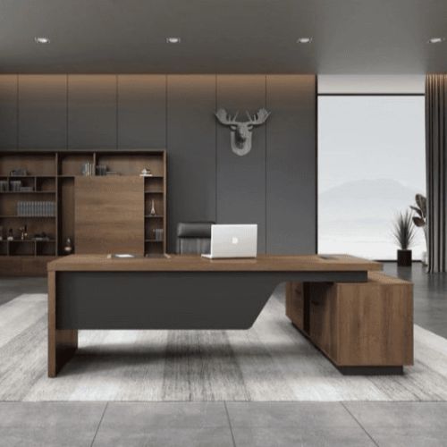 "A modern L-shaped executive desk in warm medium wood tones with a dark grey asymmetrical modesty panel."