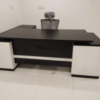 "A contemporary black and white L-shaped executive desk with thick storage pedestals and a contrasting horizontal white accent stripe on the modesty panel."