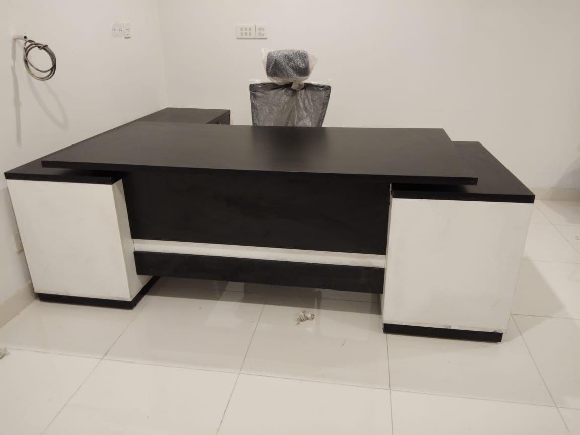 "A contemporary black and white L-shaped executive desk with thick storage pedestals and a contrasting horizontal white accent stripe on the modesty panel."