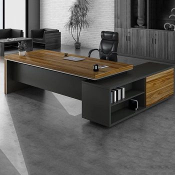 "A modern L-shaped executive desk featuring a thick teak wood floating top, a matte charcoal grey frame, and an attached side return with open shelving."