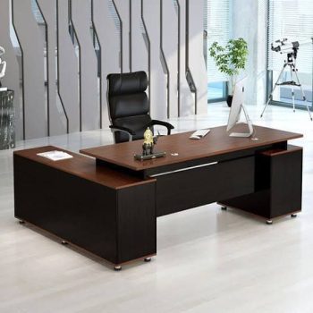 "A modern L-shaped executive desk with a warm cherry wood top surface, a matte black base, and an attached side storage return cabinet."