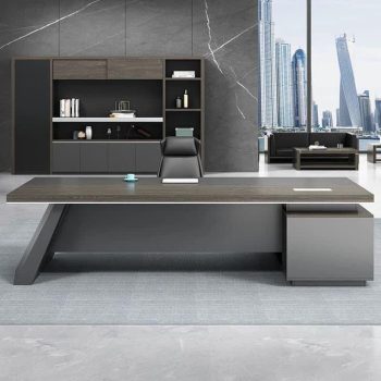 "A modern L-shaped executive desk in dark grey and grey oak wood veneer, featuring an angled leg base and a blocky side storage pedestal."