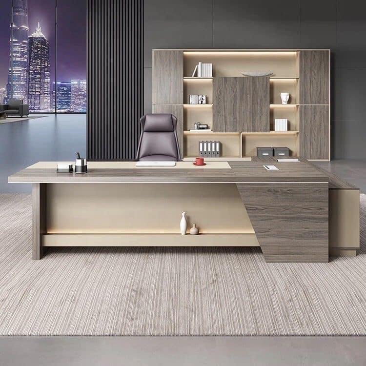 "A modern L-shaped executive desk in muted grey wood veneer and beige panels, featuring an integrated LED-lit lower display shelf."
