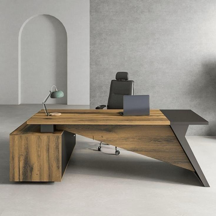 "A modern L-shaped executive desk in rustic oak wood and charcoal grey, featuring a striking, sharply angled geometric modesty panel and support leg."
