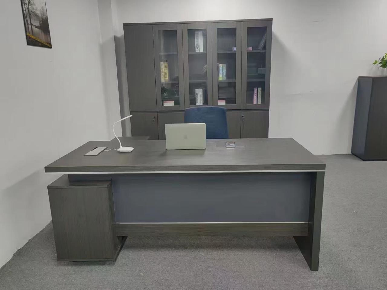 "A contemporary grey-brown wood executive desk with a blue-grey front modesty panel and a compact side pedestal cabinet."