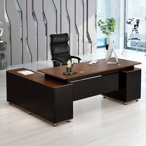 "A modern L-shaped executive desk with a warm cherry wood top surface, a matte black base, and an attached side storage return cabinet."