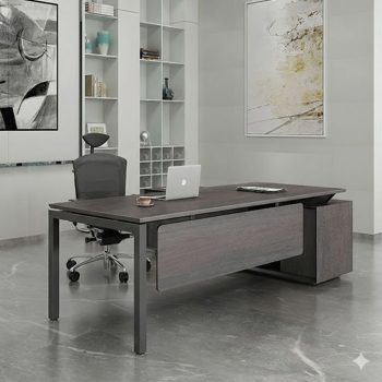 "A contemporary dark grey wood grain manager desk featuring a floating front modesty panel, slim dark metal legs, and an integrated side storage return."