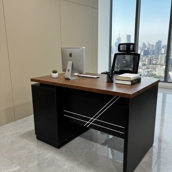 "A contemporary two-tone staff desk featuring a rich walnut rectangular top, an integrated black side return cabinet, and a solid black privacy modesty panel detailed with intersecting silver accent lines."