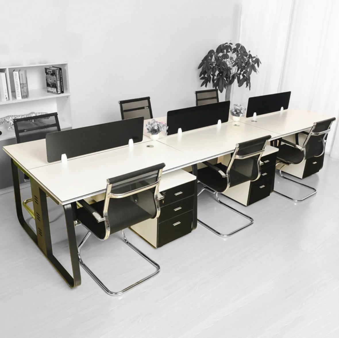 "A modular 6-person back-to-back office workstation desk featuring cream white tabletops, a curved dark gray steel frame, black rectangular privacy divider screens, and matching under-desk mobile filing cabinets."