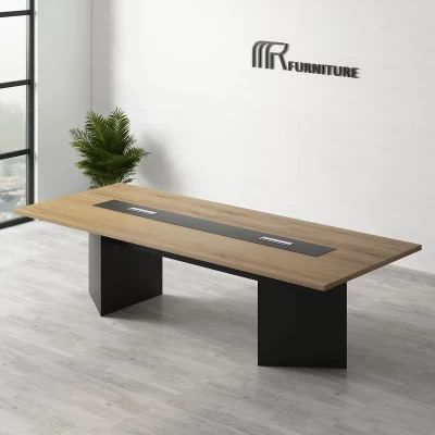 "A modern rectangular conference desk featuring a natural oak wood-grain top with a long black center media track and two thick, black angled slab pedestal bases."