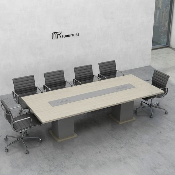"A large, rectangular conference room meeting table featuring a light wood-grain tabletop with a long, built-in silver center media track, supported by two thick gray pedestal block bases with wood-grain trim."