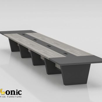 "An extra-large, multi-segment executive conference table featuring weathered gray wood-grain top panels flanked by charcoal dark gray end caps and a matching center media track, supported by a row of angled dark gray panel pedestal legs."