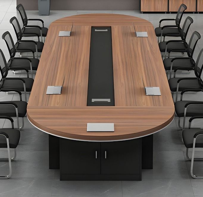 "A large, racetrack oval conference room meeting table featuring a warm teak wood-grain top with a long black center media channel, five silver power-access flip-covers, a slim white perimeter trim, and a thick black credenza-style storage base."