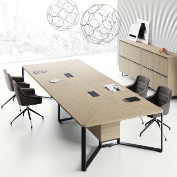 "A modern rectangular executive boardroom desk featuring a light oak wood-grain top with geometric mitered-edge detailing, two black pop-up power outlets, and a sculptural black metal open-frame base."